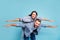 Portrait of charming people raising their hands laughing wearing denim jeans jackets isolated over blue background