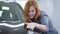 Portrait of charming redhead Caucasian woman enjoying new car. Happy young woman touching automobile and smiling