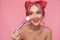 Portrait of charming shirtless woman applying cosmetics with makeup brush