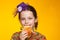 Portrait of a cheerful 8-year-old girl in a miniature hat, a multi-colored sweater and with a sandwich in hand