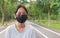 Portrait cheerful adorable Thai teen girl wears black face mask standing on the footpath in public park during COVID-19 epidemic