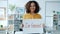 Portrait of cheerful African American girl holding feminist banner smiling standing indoors alone