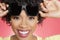 Portrait of a cheerful African American woman holding sunglasses over colored background