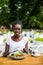 Portrait of cheerful afro american woman has dinner break, eats fresh salad dish in cafe.