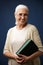 Portrait of cheerful aged woman in glasses, holding book, looking at camera