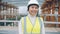 Portrait of cheerful Asial lady wearing helmet and protective vest smiling in building area