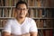 Portrait of cheerful Asian male librarian smiling, man standing against books in library