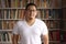 Portrait of cheerful Asian male librarian smiling, man standing against books in library