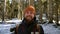 Portrait of a cheerful bearded laughing young man with a backpack standing in a coniferous winter forest