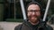 Portrait of cheerful bearded man in 30s looking to camera and posing. Close up view of handsome male person in glasses