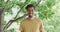 Portrait of cheerful biracial man in yellow t-shirt is standing against trees