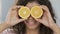 Portrait of cheerful biracial woman applying halves of orange to eyes, optimism