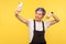 Portrait of cheerful blogger, hipster girl holding cell phone making video call or doing blog. yellow background studio shot