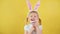 Portrait of cheerful blond little kid girl with rabbit bunny ears and protective mask