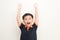 Portrait of cheerful boy with raised hands over isolated white background