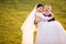 Portrait of cheerful bridegroom carrying bride on grassy field