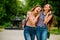 Portrait of cheerful buddies with closed eyes red lips laughing wearing striped t-shirt denim jeans in town outside