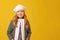 Portrait of a cheerful child in a gray coat and beret on a yellow background. Little girl blonde looks into the camera.