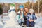 Portrait of a cheerful family with snowman. happy mother and children in the winter outdoors.