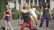 Portrait of cheerful female fitness instructor in red legging and black top smiling as dancing to disco music with group