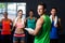 Portrait of cheerful fitness instructor with people in gym