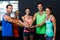 Portrait of cheerful friends putting hands together in gym