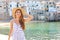 Portrait of cheerful girl in seaside town overlooking sea looking at camera