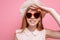 Portrait of a cheerful girl in a summer hat and heart-shaped sunglasses waiting for a vacation