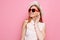 Portrait of a cheerful girl in a summer hat and heart-shaped sunglasses waiting for a vacation