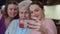 Portrait of cheerful glad Caucasian young woman taking selfie on smartphone with grandmother and mother. Happy smiling