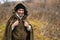 Portrait of cheerful hiker man wearing green raincoat tent standing in thicket of bushes in cold overcast day and