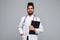 Portrait of a cheerful Indian male doctor holding a medical chart over white background