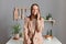 Portrait of cheerful joyful brown haired woman wearing beige suit standing near table on kitchen at home, looking at camera,