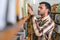 Portrait of cheerful male international Indian student with backpack, learning accessories standing near bookshelves at