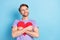 Portrait of cheerful man arms hold hugging paper heart postcard look empty space isolated on blue color background