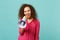 Portrait of cheerful pretty african girl in pink casual clothes scream in megaphone isolated on blue turquoise wall