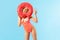 Portrait of cheerful pretty woman in swimsuit looking through big donut rubber ring and showing victory