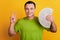 Portrait of cheerful rich guy show v-sign hold money fan on yellow background