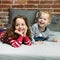 Portrait of cheerful siblings relaxing in bedroom