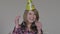 Portrait of cheerful woman in party hat and headphones rejoicing. Young joyful girl clapping hands, showing thumbs up