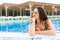 Portrait of cheerful woman relaxing at the luxury poolside. Girl at travel spa resort pool. Summer vacation.
