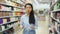 Portrait of cheerful young Asian woman behind counter demonstrating hair dye products