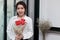 Portrait of cheerful young Asian woman holding a bouquet of red roses in office.