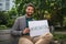 Portrait of cheerful young man holding banner outdoors in city, covid-19 vaccination campaign.