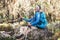 Portrait of a cheerfully laughing African-American Ethnicity young man sitting with a backpack and trekking poles and resting in