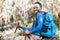 Portrait of a cheerfully smiling African-American Ethnicity young man sitting with a backpack and trekking poles and resting in