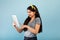 Portrait of cheery Indian teenage girl using modern tablet pc over blue studio background