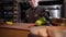 Portrait chef chopping with sharp knife green and yellow bell pepper on the wooden board to prepare salad in big plate