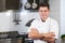 Portrait Of Chef Wearing Whites Standing By Cooker In Kitchen