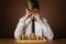 Portrait of Chess Business Player thinking and looking at Chessboard Pieces covering Face by Hands. Intelligent Boy Stressed